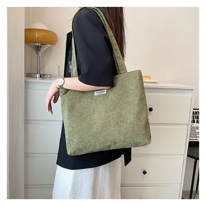 Detail view of the green corduroy tote bag with fashion label and textured fabric