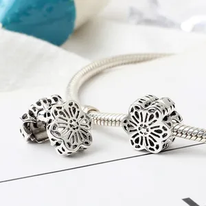 Macro shot of silver hollow floral bead charms on a snake chain bracelet detail