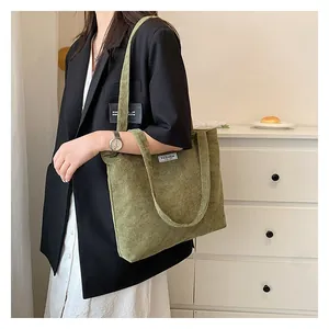 Detail of green corduroy tote bag showing striped texture and white Fashion woven label