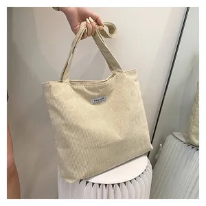 Detail of off-white corduroy tote bag showing the soft texture and fashion label tag