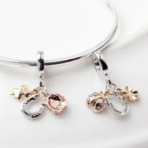 Silver horseshoe clover and ladybug pendant charms on a polished metal bangle
