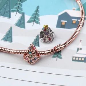 Nahaufnahme eines roségoldenen Schlangenarmbandes mit glitzernden Weihnachtsbaum-Anhängern