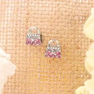 Makro-Detail von silbernen Handtaschen-Anhängern mit rosa Strass und kleinem Schleifen-Design