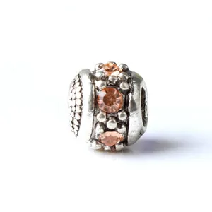 Macro shot of retro silver charm bead featuring orange crystals and textured grid patterns