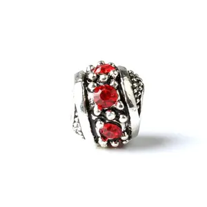 Macro detail of retro silver charm bead featuring faceted red crystals and oxidation finish