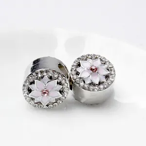 Dettaglio di due charm magnolia in argento con fiori in smalto rosa e zirconi