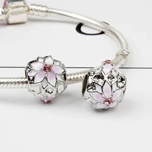 Dettaglio macro del bracciale a maglia蛇 con perline smaltate floreali e cristalli rosa