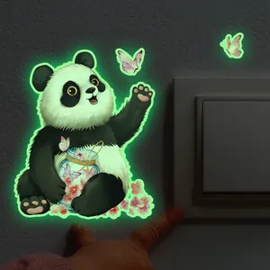 Sticker panda phosphorescent avec papillons brillant à côté d'un interrupteur mural