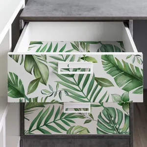 Detail of tropical green leaf wall stickers applied to modern white furniture drawers