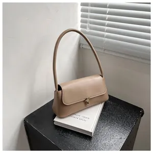 Close-up of minimalist khaki baguette bag with golden square lock and slim handle