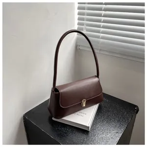 Detail of dark brown baguette bag with golden metal buckle on minimalist background