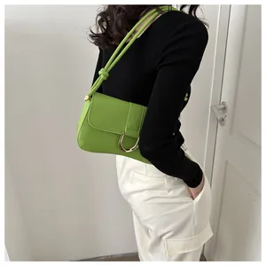 Detail of a bright green faux leather shoulder bag featuring a gold horseshoe buckle