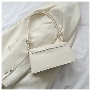 Detail of cream white leather shoulder bag with knot handle on textured blazer