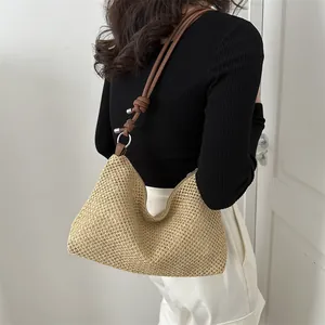 Chic woven straw tote bag with brown leather shoulder strap and knot detail for summer