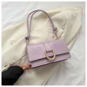 Detailed view of lavender purple baguette bag with gold horseshoe buckle on blazer background