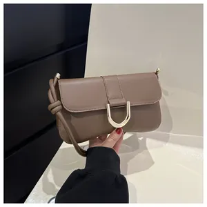 Detailed close-up of taupe leather bag with decorative gold D-ring buckle and knotted strap
