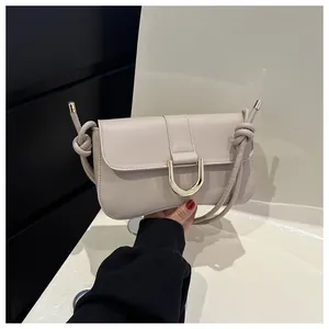 Detail of beige leather bag with golden U-shaped buckle and unique knotted shoulder strap