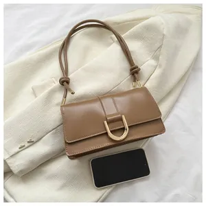 Detail of khaki baguette bag with gold metal buckle and knotted strap on a blazer
