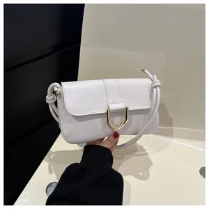 Detail of white baguette bag featuring a U-shaped gold metal buckle and knotted shoulder strap