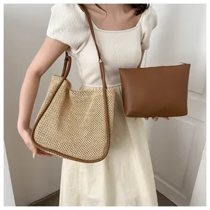 Dettaglio della borsa tote in paglia intrecciata e pochette in pelle marrone