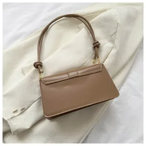 Detail showing the brown faux leather texture and decorative knots on the shoulder bag straps