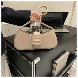 Minimalist beige baguette bag showing side view with cylindrical handle on office desk