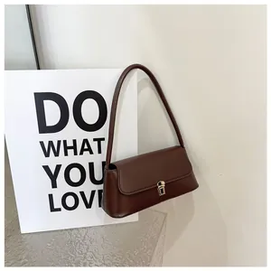 Close-up of brown baguette bag with golden buckle and smooth faux leather texture
