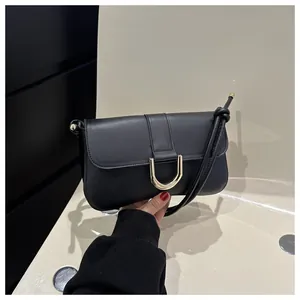 Detail shot of black matte leather shoulder bag with elegant gold U-shaped metal buckle