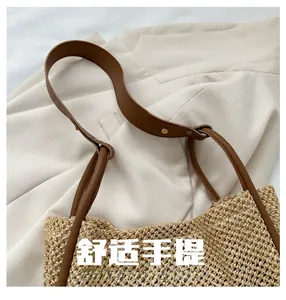 Dettagli della borsa tote in paglia con manici in pelle marrone e rivetti metallici