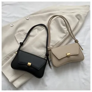 Detail of minimalist baguette bags in black and beige with gold clasps and knotted straps