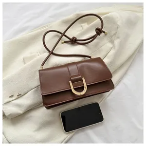 Detail view of a brown vintage leather shoulder bag with gold hardware and phone for scale