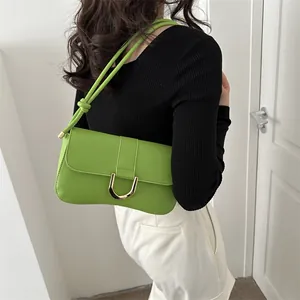 Detail of green leather underarm bag with gold U-shaped buckle on female model