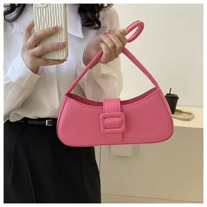 Chic rose pink baguette bag with large buckle detail worn by a model in a casual setting