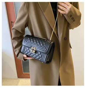 Detail of black quilted leather square bag with gold chain strap and vintage metal lock