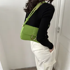 Detail of green leather shoulder bag with golden U-shaped buckle and knotted strap