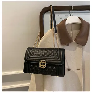 Detail of black quilted leather shoulder bag with gold chain and metal buckle