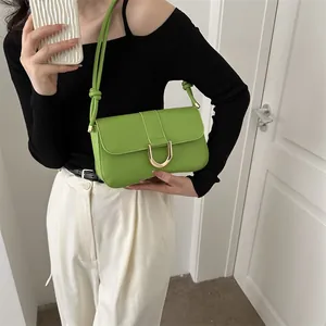 Close-up of grass green shoulder bag featuring a golden U-shaped metal buckle and knot strap