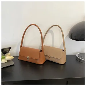 Detail of trendy baguette underarm bags in caramel and apricot with gold metal buckles