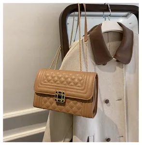 Detail of khaki quilted crossbody bag featuring vintage gold clasp and chain strap