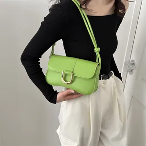 Detailed view of neon green leather underarm bag with decorative gold U-shaped metal buckle