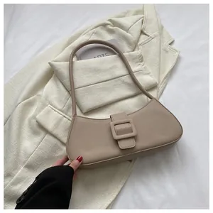Detailed view of beige baguette bag with matte leather and large buckle on neutral blazer