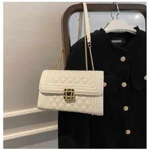Close-up of white quilted leather chain bag with elegant black and gold square buckle
