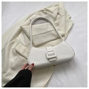 Detail of white leather baguette bag with square buckle on cream fabric background