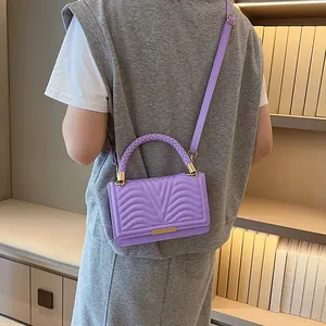 Chic purple quilted crossbody bag with woven handle shown on model in a modern interior