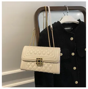 Detailed view of cream quilted shoulder bag with gold gemstone lock on tweed jacket