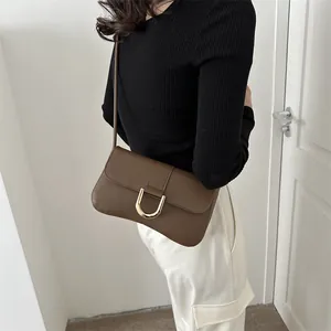 Detail of a dark brown leather shoulder bag featuring a gold U-shaped metal clasp