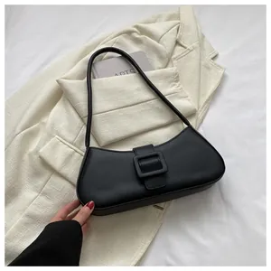 Close-up of a black matte baguette bag with a stylish square buckle on a beige blazer
