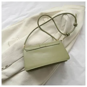 Detail view of light green leather baguette bag on blazer with knotted strap finish