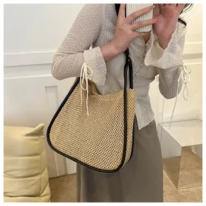 Dettaglio borsa tote in paglia con bordo nero e coulisse bianca indossata dalla modella