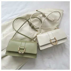 Detail of minimalist leather baguette bags with gold horseshoe buckles on beige fabric